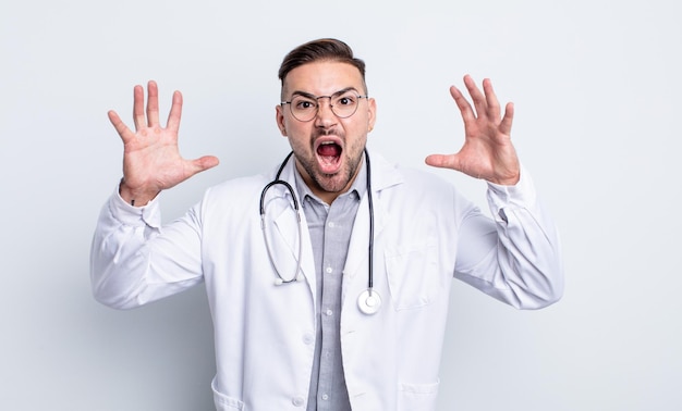 Young handsome man screaming with hands up in the air. physician concept