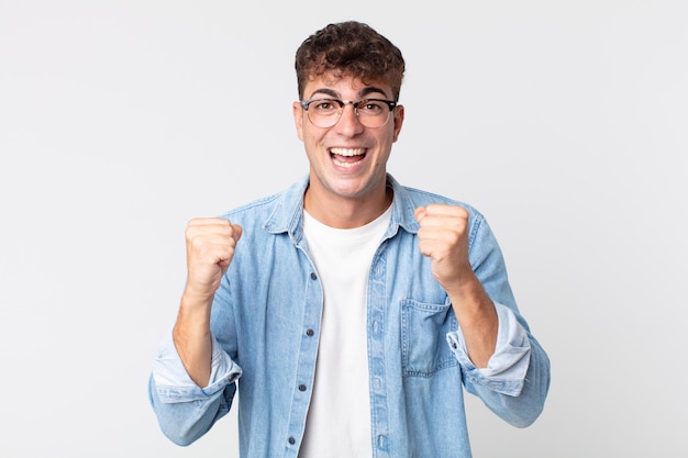 Young handsome man shouting triumphantly, laughing and feeling happy and excited while celebrating success