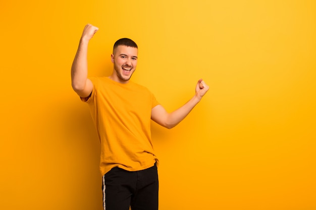 Young handsome man shouting triumphantly, looking like excited, happy and surprised winner, celebrating on flat