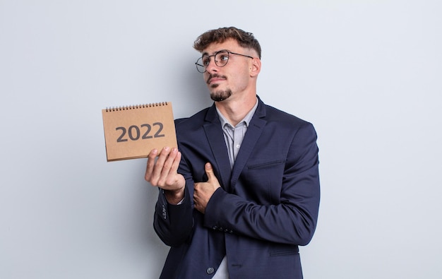 Photo young handsome man shrugging, feeling confused and uncertain. calendar concept