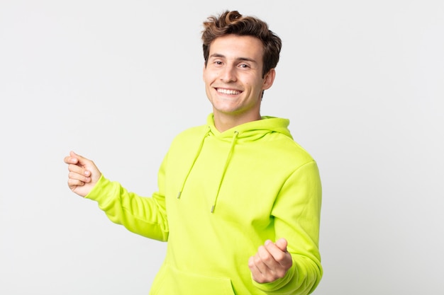 Young handsome man smiling, feeling carefree, relaxed and happy, dancing and listening to music, having fun at a party