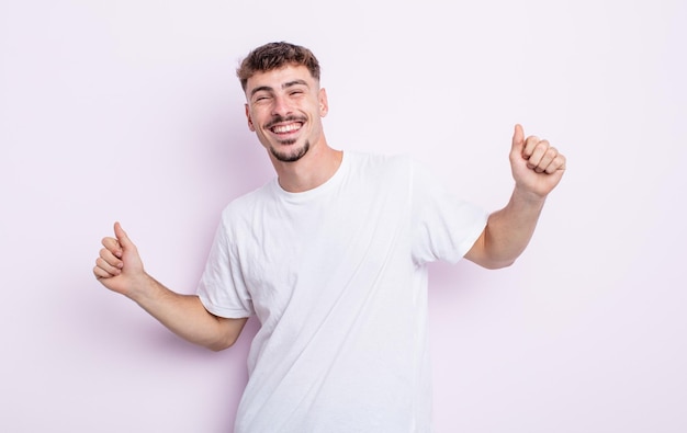 Young handsome man smiling, feeling carefree, relaxed and happy, dancing and listening to music, having fun at a party