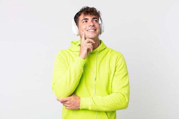 Young handsome man smiling happily and daydreaming or doubting and headphones