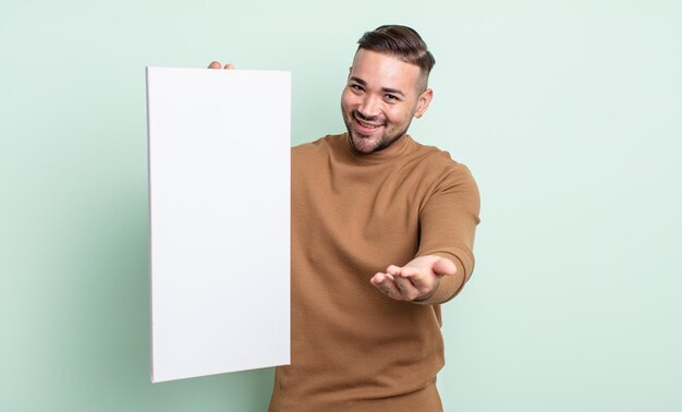 Young handsome man smiling happily with friendly and  offering and showing a concept. empty canvas concept