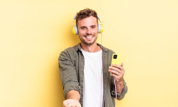 Young handsome man smiling happily with friendly and  offering and showing a concept headphones and smartphone concept