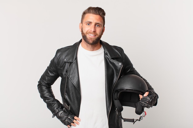 Young handsome man smiling happily with a hand on hip and confident. motorbike helmet concept