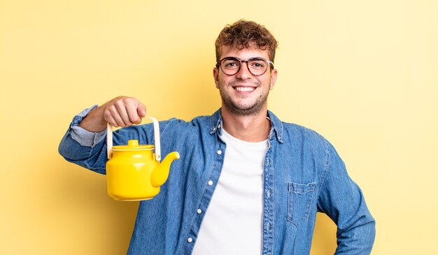 Young handsome man smiling happily with a hand on hip and confident.teapot concept