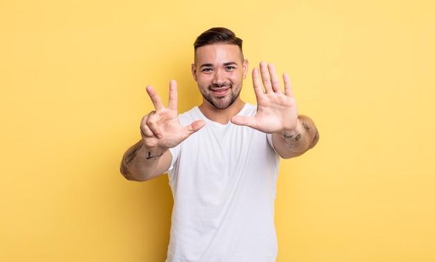 Young handsome man smiling and looking friendly showing number eight or eighth with hand forward counting down