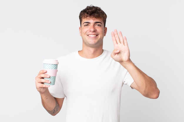 Young handsome man smiling and looking friendly, showing number four and holding a take away coffee