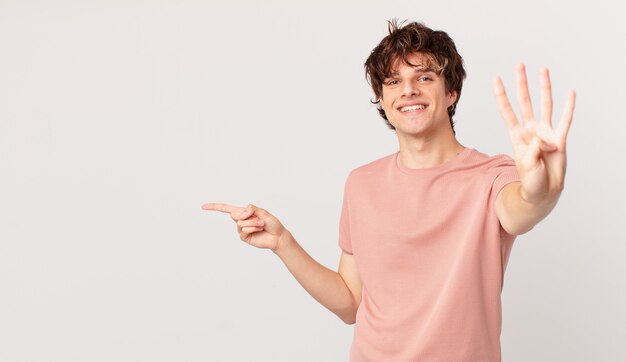 Young handsome man smiling and looking friendly, showing number four