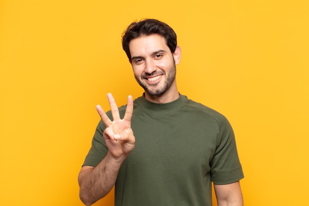 Young handsome man smiling and looking friendly, showing number three or third with hand forward, counting down