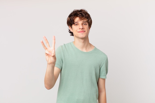 Young handsome man smiling and looking friendly, showing number three