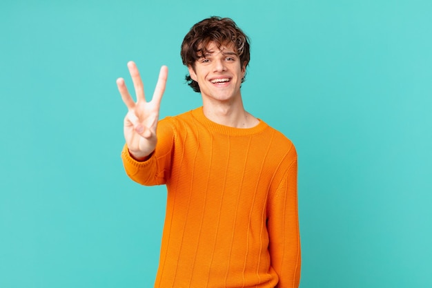 Young handsome man smiling and looking friendly, showing number three