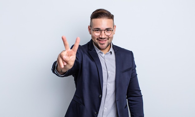 Young handsome man smiling and looking happy, gesturing victory or peace. businessman concept