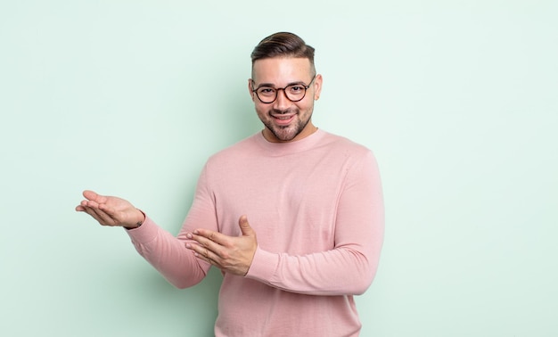 Young handsome man smiling proudly and confidently, feeling happy and satisfied and showing a concept on copy space