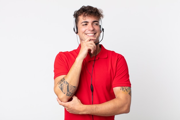 young handsome man smiling with a happy, confident expression with hand on chin. telemarketer concept