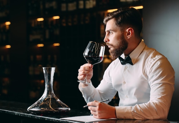 Young handsome man sommelier tasting red wine in cellar.