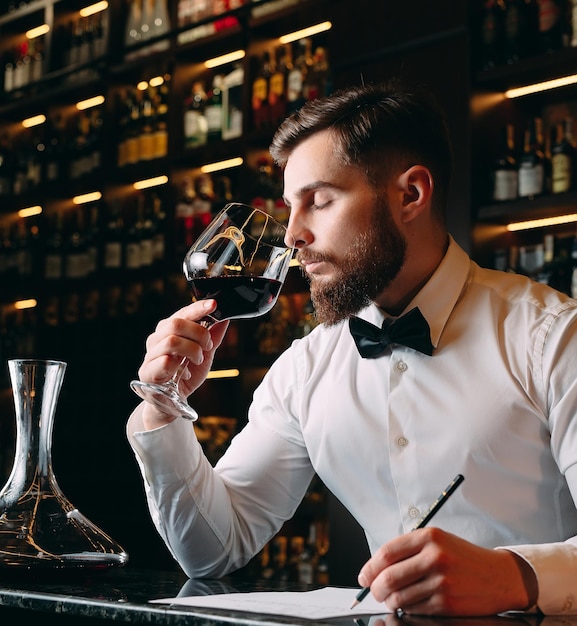 Young handsome man sommelier tasting red wine in cellar.