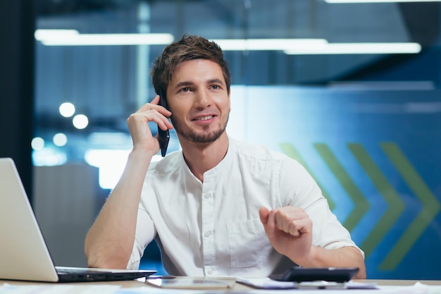 Young handsome man specialist working in the office at the desk Talking on a mobile phone with customers with bank with business partners