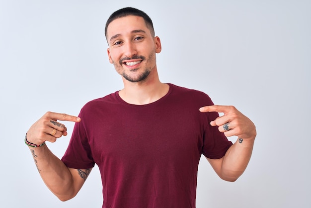 Young handsome man standing over isolated background looking confident with smile on face pointing oneself with fingers proud and happy