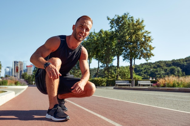 Young handsome man in a starting position for running on a sports track