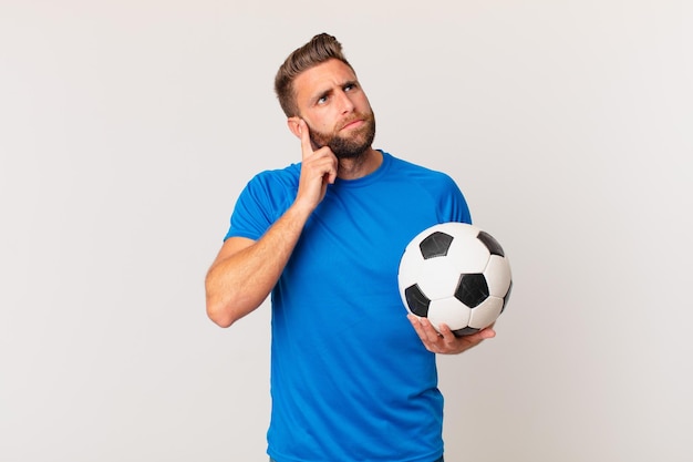 Young handsome man thinking, feeling doubtful and confused. soccer concept