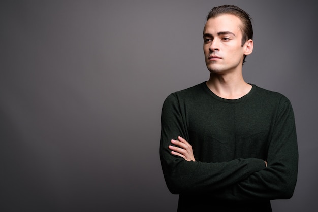 Young handsome man thinking and looking up with arms crossed