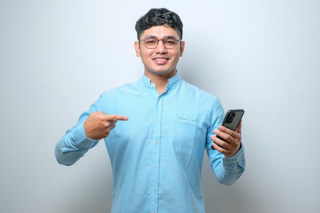 Young handsome man using smartphone very happy pointing with hand and finger