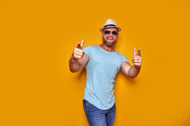 Young handsome man wearing casual tshirt standing over isolated yellow background pointing with fing...