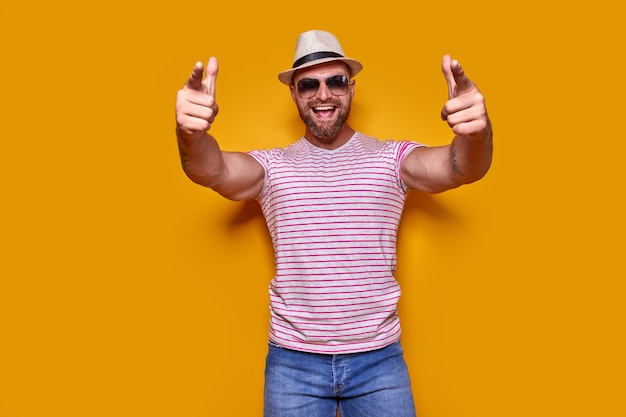 Young handsome man wearing casual tshirt standing over isolated yellow background pointing with fing...