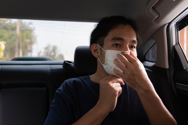 Young handsome man wearing protective face mask for protect himself from the coronavirus while sit in car.