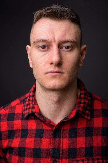 young handsome man wearing red checkered shirt on gray