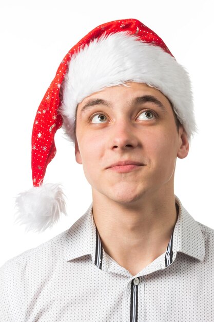 Young handsome man wearing a Santa hat over white background surprised showing and pointing something that is on her hand