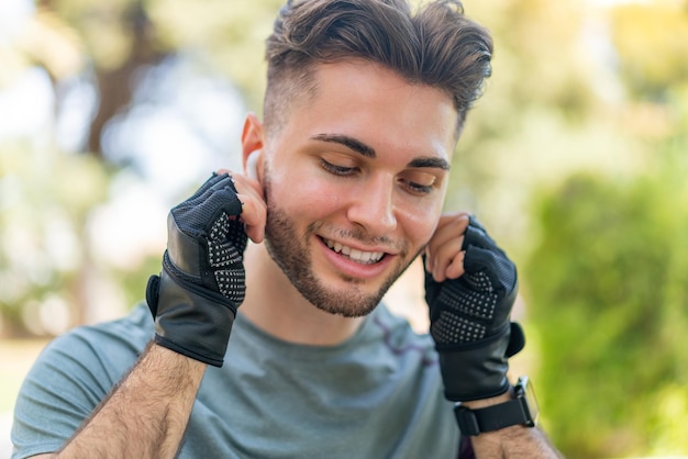 Young handsome man wearing sport wear and listening music with wireless headphones