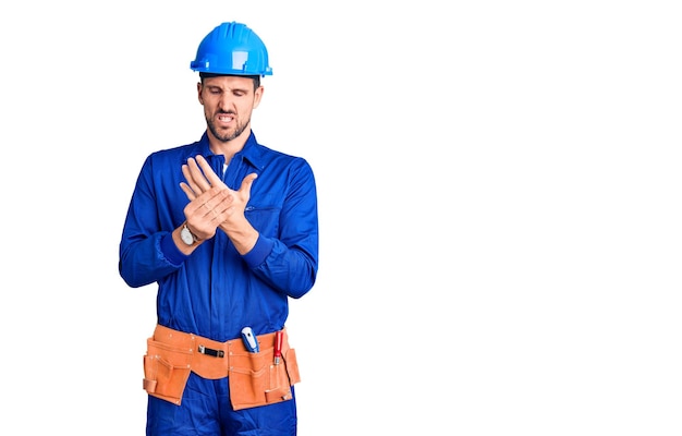 Young handsome man wearing worker uniform and hardhat touching painful neck sore throat for flu clod and infection