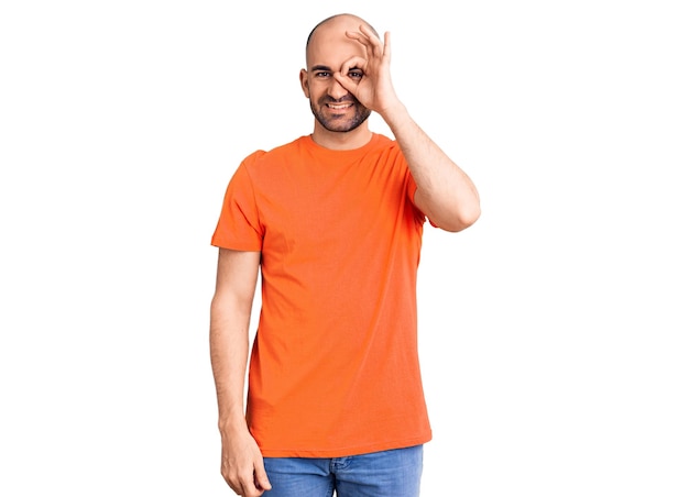 Young handsome man wering casual t shirt doing ok gesture with hand smiling eye looking through fingers with happy face