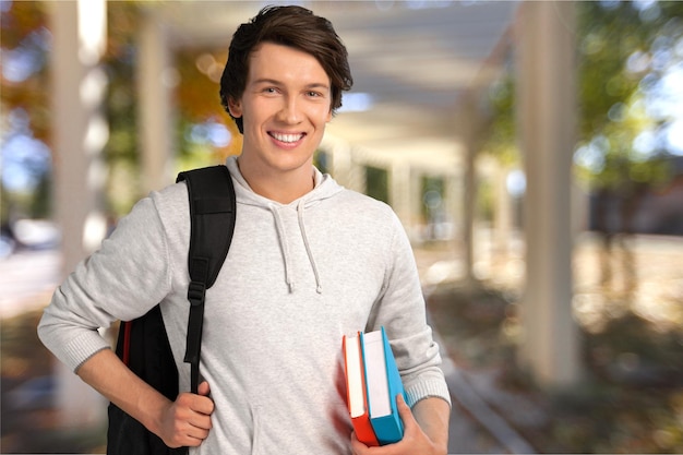 Young handsome man with backpack holding books