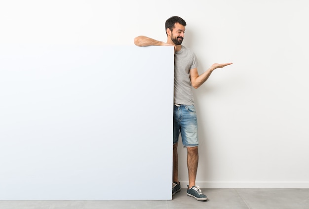 Young handsome man with beard holding a big empty placard 