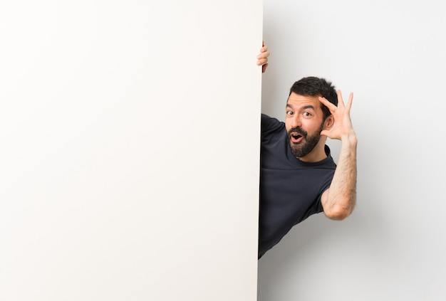 Young handsome man with beard holding a big empty placard