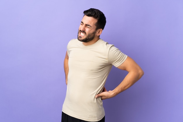 Young handsome man with beard over isolated background suffering from backache for having made an effort