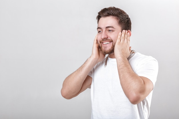 Young handsome man with beard in tshirt listening to music on headphones