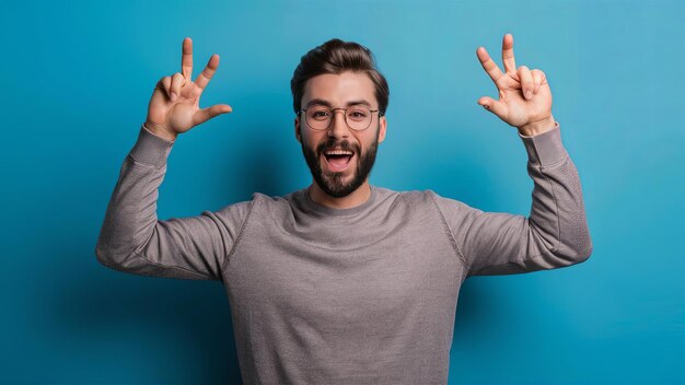 Photo a young handsome man with a beard wearing a casual sweater and glasses stands against a blue backgro