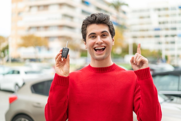 Young handsome man with car key pointing up a great idea