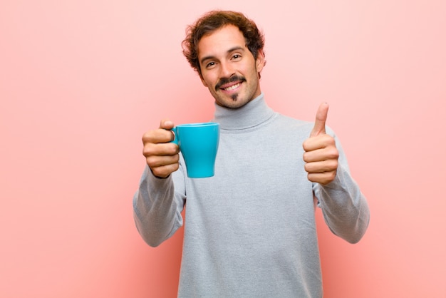 Young handsome man with a coffee cup against pink flat wall