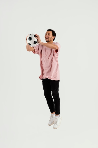 Young handsome man with football ball jumping