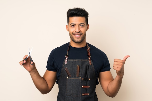 Young handsome man with hairdresser or barber dress with thumb up