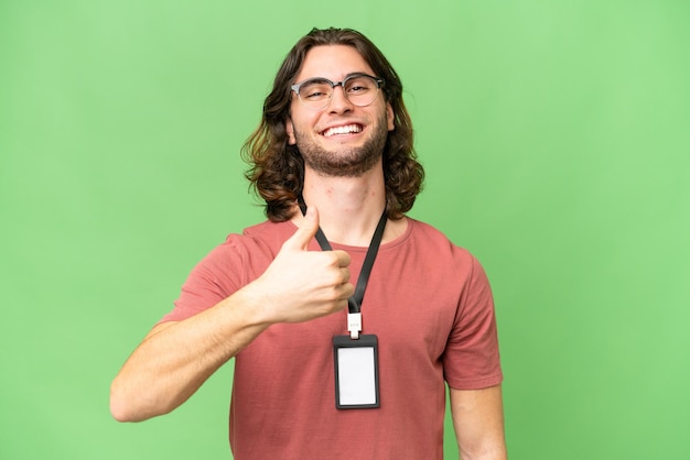 Young handsome man with ID card over isolated background giving a thumbs up gesture