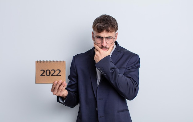 Young handsome man with mouth and eyes wide open and hand on chin. calendar concept