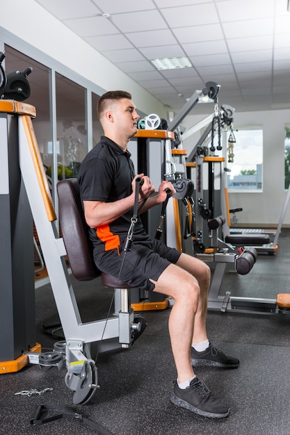 Young handsome man working out and doing exercises at gym room in fitness center