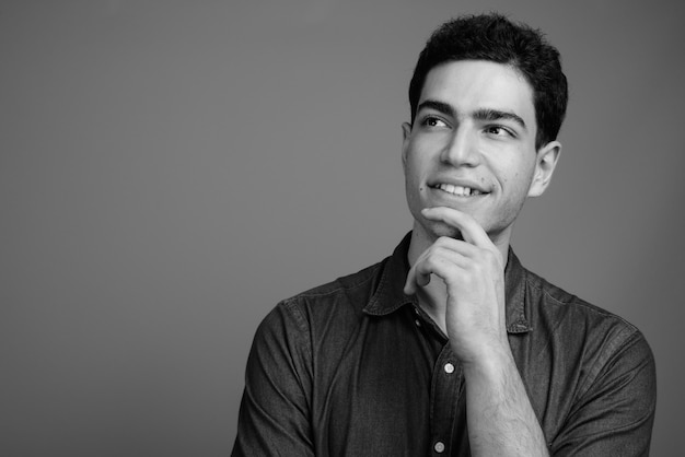 young handsome Persian businessman against gray wall in black and white